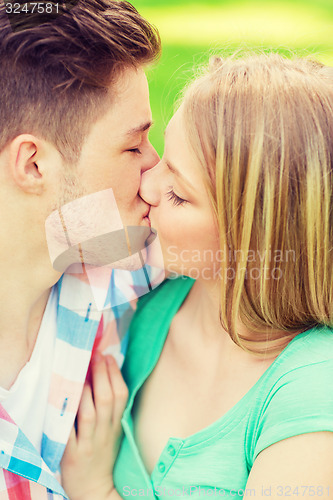 Image of smiling couple kissing and hugging in park