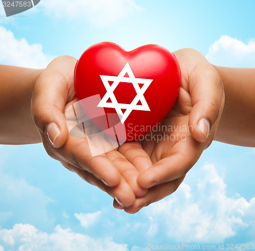 Image of close up of hands holding heart with jewish star