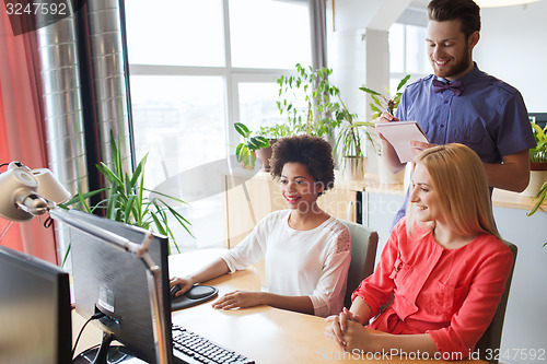 Image of happy creative team with computer in office