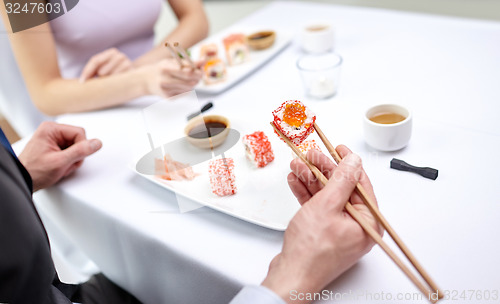 Image of close up of couple eating sushi at restaurant