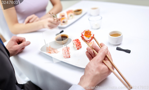 Image of close up of couple eating sushi at restaurant