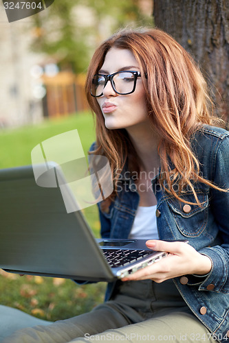 Image of happy student girl writing to notebook at campus