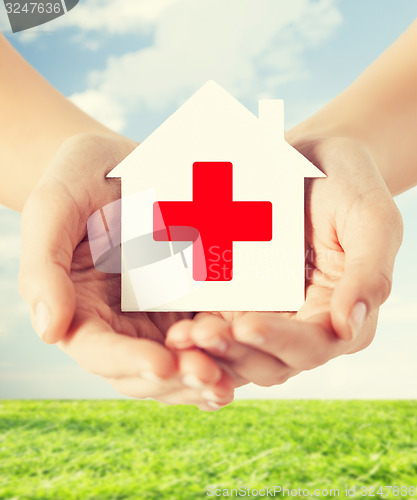 Image of hands holding paper house with red cross