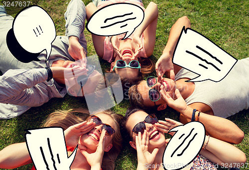 Image of group of smiling friends lying on grass outdoors