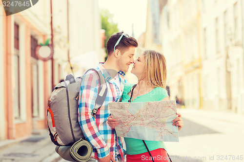 Image of smiling couple with map and backpack in city