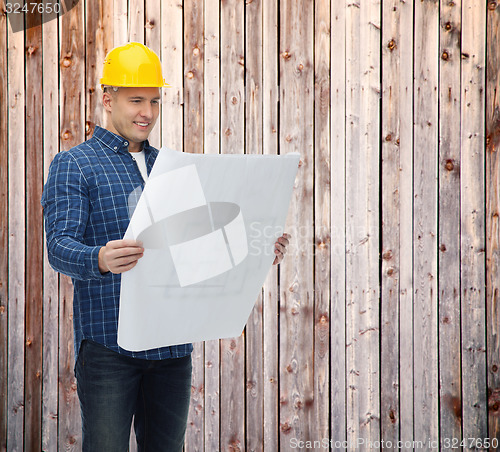 Image of smiling male builder in helmet reading blueprint