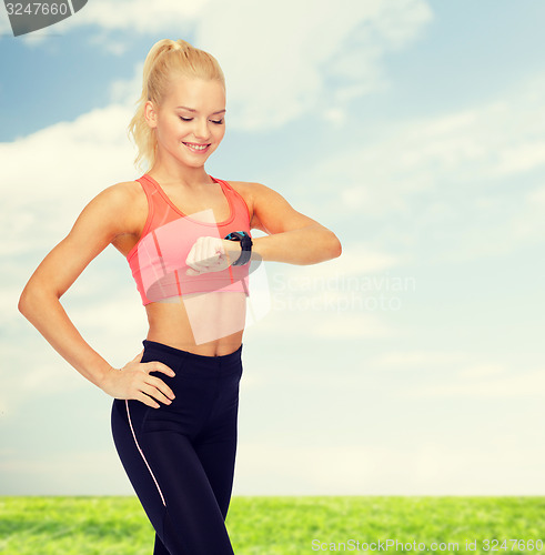 Image of smiling woman with heart rate monitor on hand