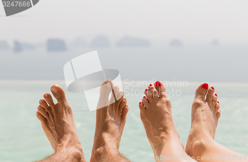 Image of closeup of couple feet over sea and sky on beach