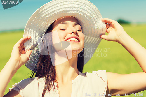 Image of smiling young woman in straw hat outdoors