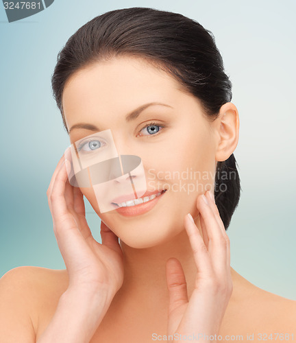 Image of beautiful young woman touching her face