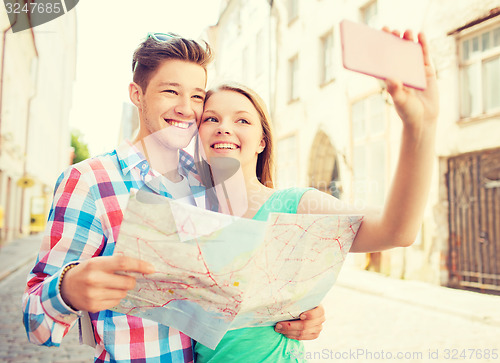 Image of smiling couple with smartphone in city