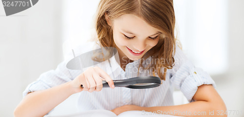 Image of girl reading book with magnifier at school