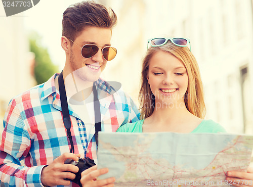 Image of smiling couple with map and photo camera in city