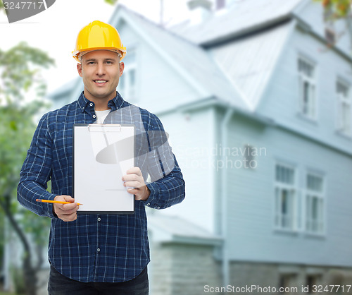 Image of smiling male builder in helmet with clipboard