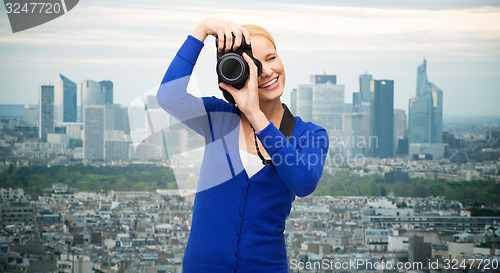 Image of smiling woman taking picture with digital camera