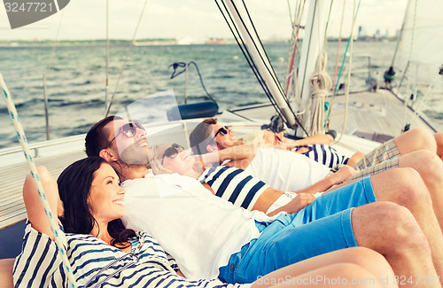 Image of smiling friends lying on yacht deck