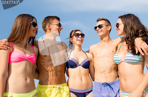 Image of smiling friends in sunglasses on summer beach