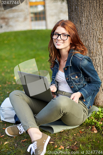 Image of happy student girl writing to notebook at campus