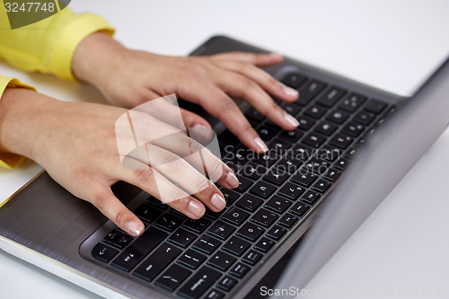 Image of close up of female hands with laptop typing