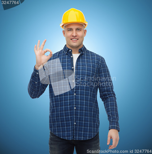 Image of smiling male builder in helmet showing ok sign