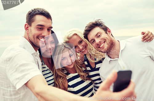 Image of happy friends on beach and taking selfie
