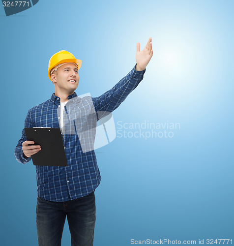 Image of smiling male builder in helmet with clipboard