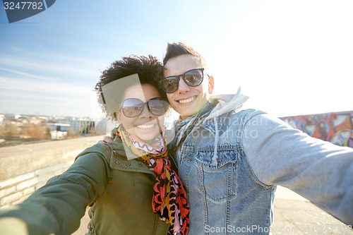 Image of happy teenage couple taking selfie on city street