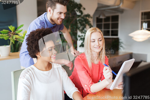 Image of happy creative team with computer in office