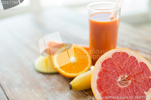 Image of close up of fresh juice glass and fruits on table