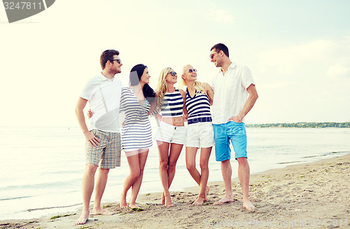 Image of smiling friends in sunglasses talking on beach