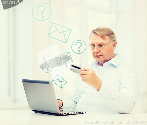 Image of old man with laptop and credit card at home