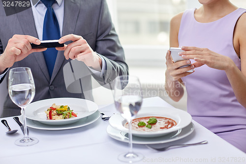 Image of close up of couple with smartphones at restaurant