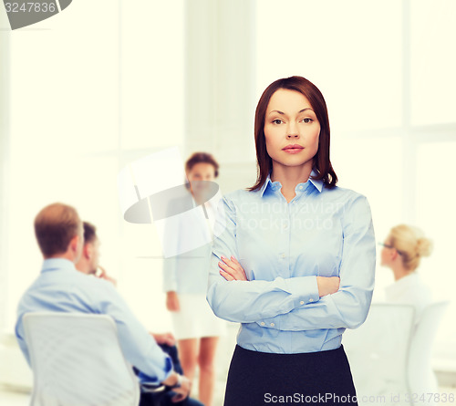 Image of smiling businesswoman with crossed arms at office