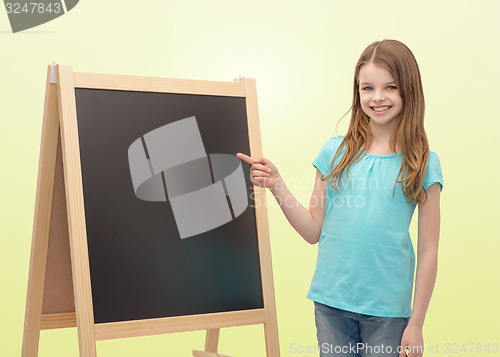 Image of happy little girl with blackboard and chalk