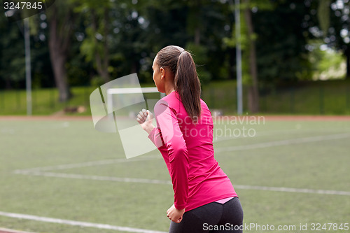 Image of woman running on track outdoors from back