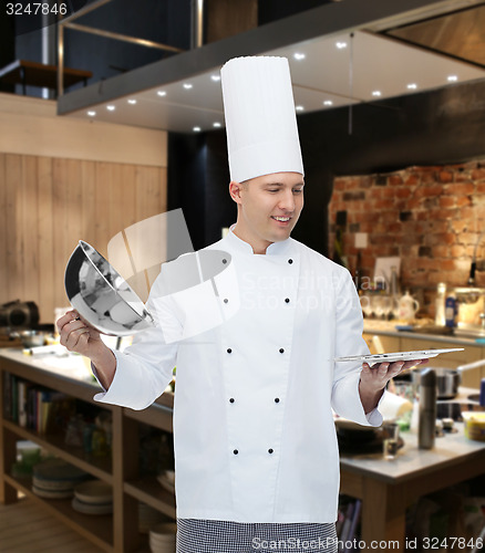 Image of happy male chef cook opening cloche