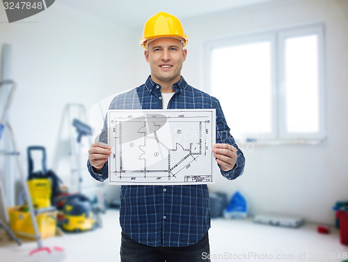 Image of smiling male builder in helmet with blueprint