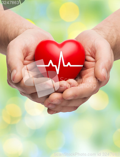 Image of close up of hands holding heart with cardiogram