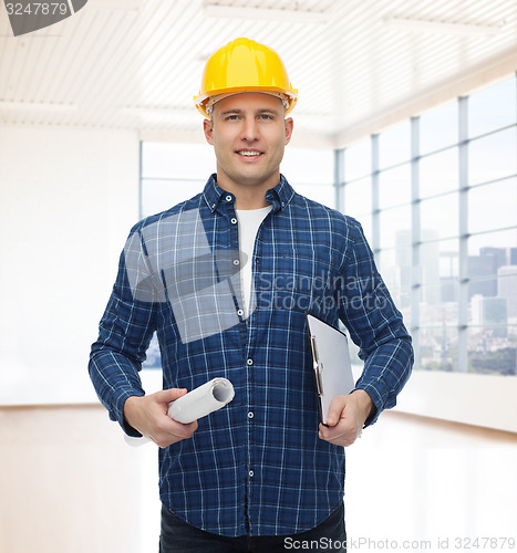 Image of smiling male builder in helmet with blueprint