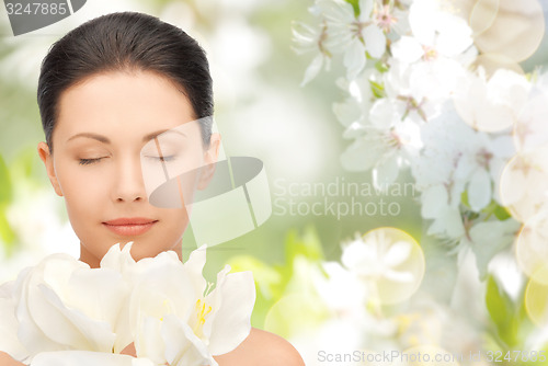 Image of beautiful woman smelling flowers with closed eyes