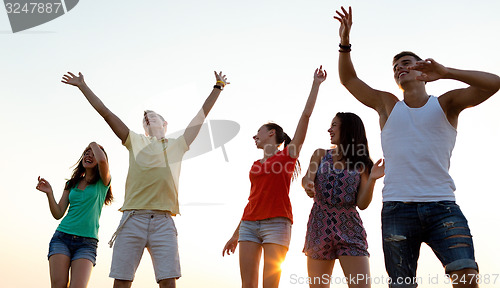 Image of smiling friends dancing on summer beach