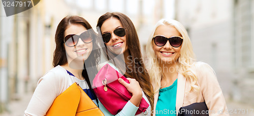 Image of three smiling women with bags in the city