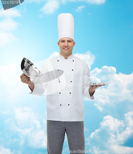 Image of happy male chef cook opening cloche