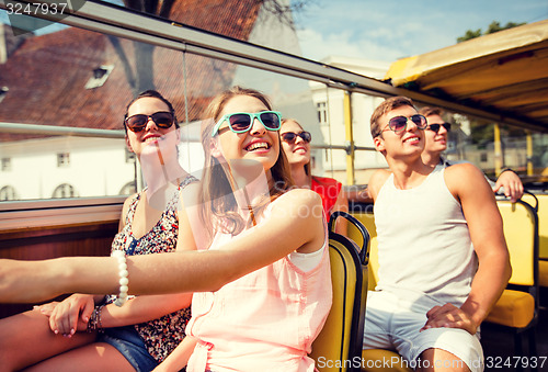 Image of group of smiling friends traveling by tour bus