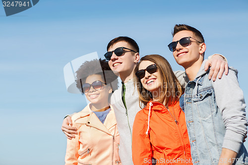 Image of happy teenage friends in shades hugging outdoors