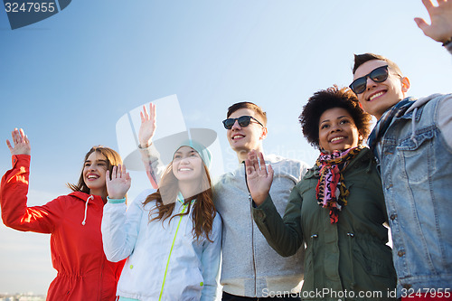 Image of happy teenage friends in shades waving hands