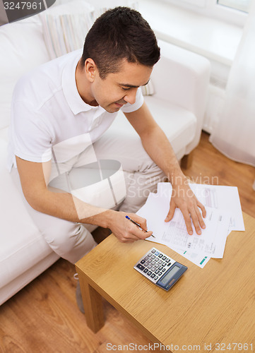 Image of man with papers and calculator at home