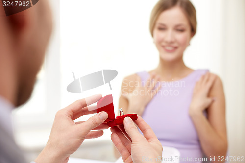 Image of excited young woman and boyfriend giving her ring