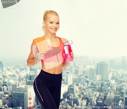 Image of smiling sporty woman with water bottle and towel