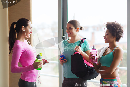 Image of happy women with bottles of water in gym